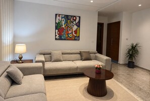 A modern living room with a sofa, a coffee table, a lamp, and a colorful abstract painting on the wall. - Elegant Apartment (Tunis)