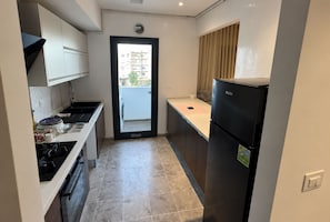 A compact kitchen with a gas stove, a refrigerator, and a sink. - Elegant Apartment (Tunis)