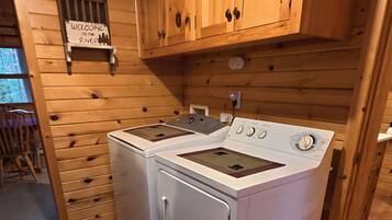 Een praktische keuken met houten kastjes, een wasmachine en een fornuis.