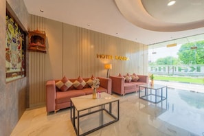Een hotel lobby met een receptiebalie, twee banken, een salontafel en een groot raam met uitzicht op de omgeving.