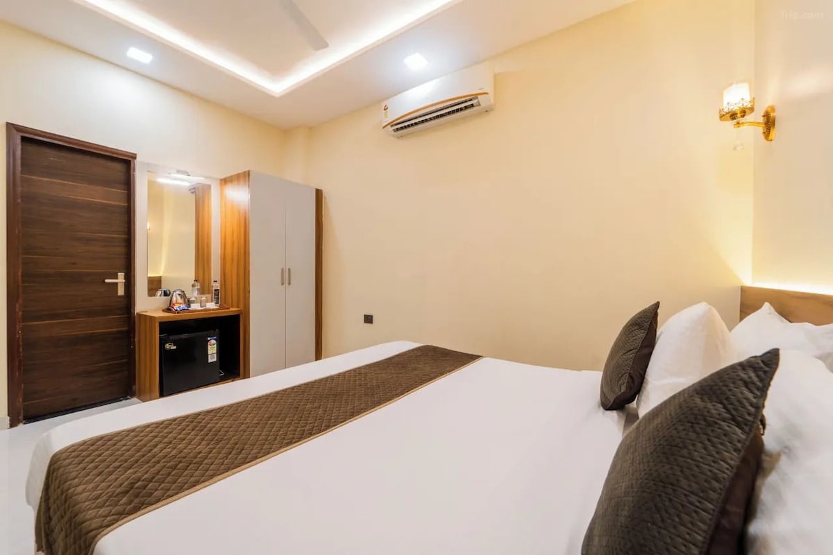 Een hotelkamer met een bed, een kledingkast, een kaptafel met spiegel, een airconditioning en een wandlamp.
