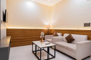Een moderne hotelkamer met een witte bank, een klein tafeltje met een vaas en een lamp.