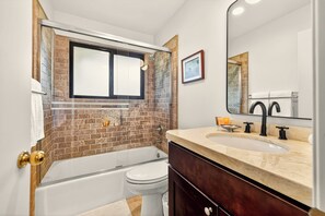 Un bagno con vasca, servizi igienici e lavandino.
