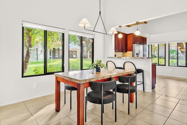 Una cucina moderna con zona pranzo, ampie finestre e vista su un paesaggio verde.
