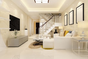 A modern living room with a sofa, coffee table, and a TV mounted on the wall.