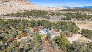 A two-story house with a large porch, surrounded by dense trees and a mountainous backdrop. - Peaceful Country Retreat in Regina (Regina)