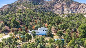 A white building with a gabled roof surrounded by dense trees and a mountainous backdrop. - Peaceful Country Retreat in Regina (Regina)