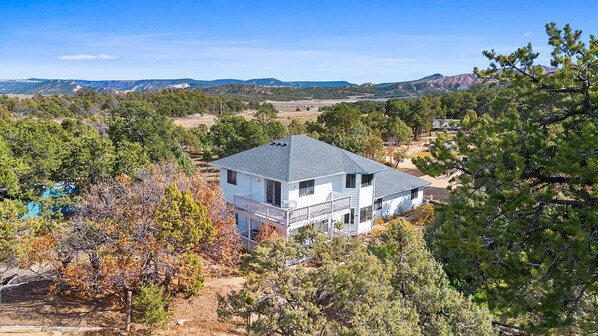 A two-story house with a balcony, surrounded by trees and a hilly landscape. - Peaceful Country Retreat in Regina (Regina)
