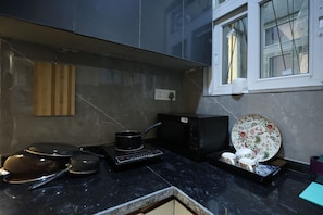 A kitchen with a microwave, kettle, and various dishes on the counter. - Forest view 1BHK Premium studio appartment (New Delhi)