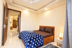 A bedroom with a bed, a nightstand, a lamp, and a ceiling fan. - Forest view 1BHK Premium studio appartment (New Delhi)