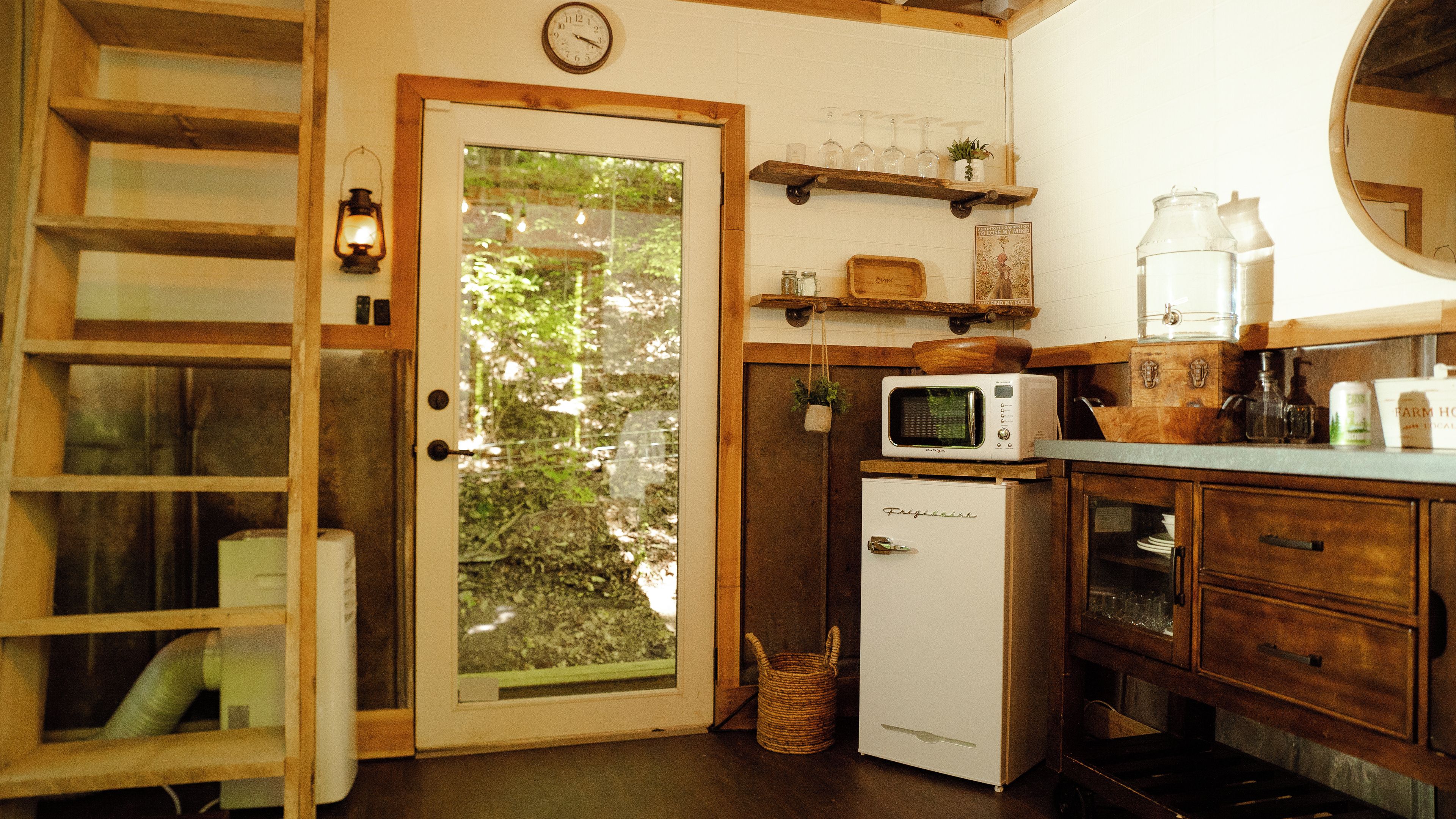 Una cocina compacta con refrigerador, microondas y estantes de madera.