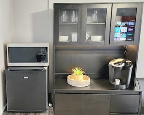 A compact kitchenette with a refrigerator, a coffee maker, and a small television. - Private King Studio near Beach, FLL & Hard Rock (Hollywood)