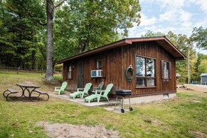 A wooden cabin with a porch, outdoor seating, and a grill. - Cozy Corner at Sommer Dorf (West Branch)