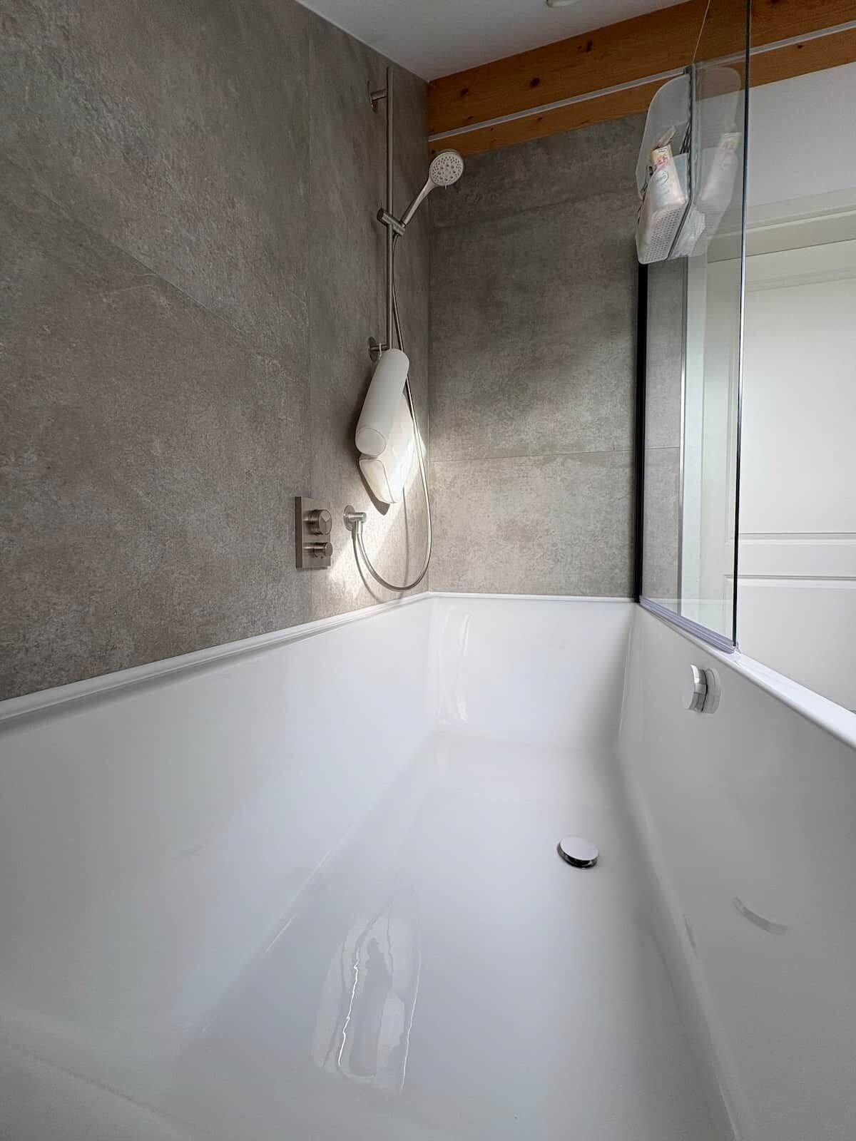 Ein modernes Badezimmer mit einer großen Badewanne, einer Duschbrause und einer Glaskabine.