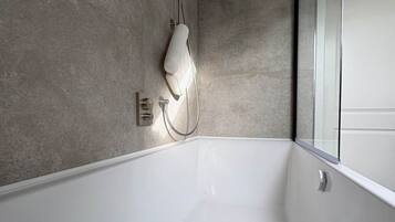 Ein modernes Badezimmer mit einer großen Badewanne, einer Duschbrause und einer Glaskabine.