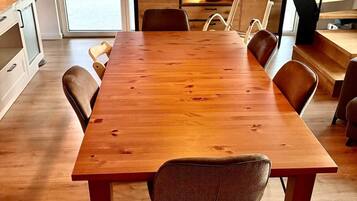 Un vaste espace dédié à la salle à manger, avec une longue table en bois et de nombreuses chaises, un escalier et une vue sur l’extérieur.