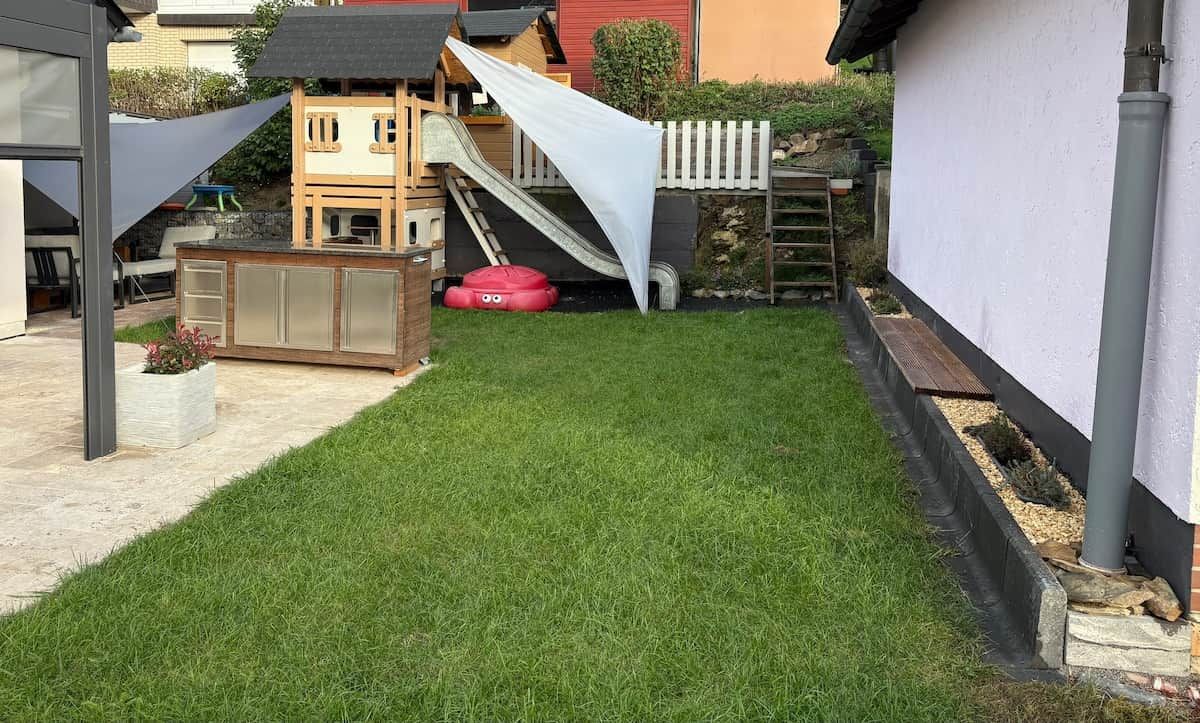 A backyard with a play area, including a slide and a small wooden structure.