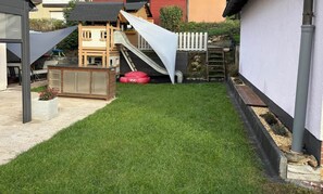 A backyard with a play area, including a slide and a small wooden structure.