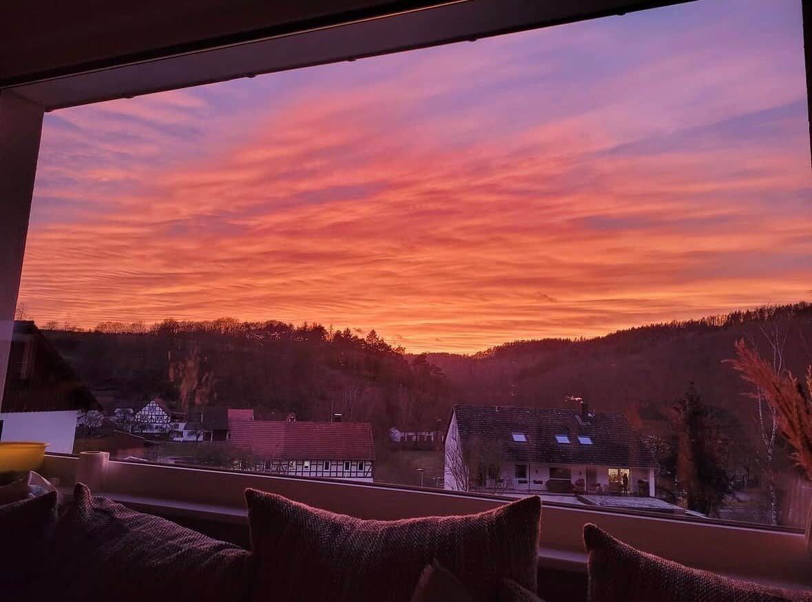 A view from a window overlooking a village at sunset with houses and a road visible.
