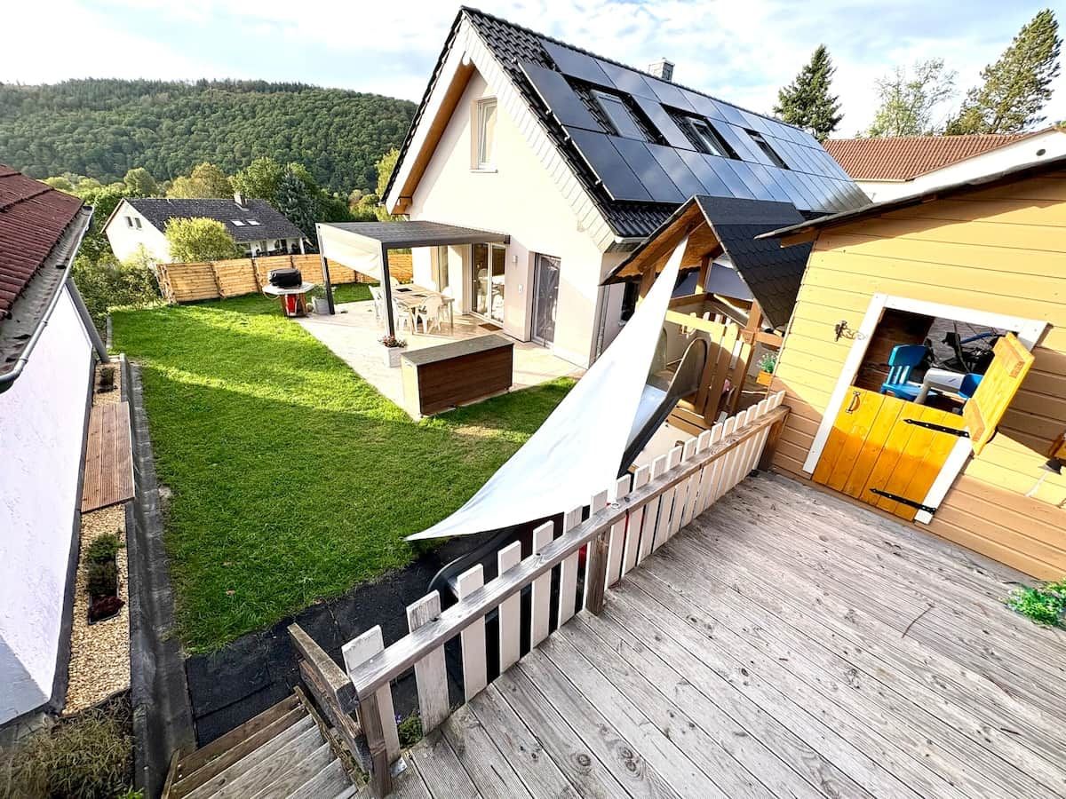 A residential property with a sloped roof, a wooden deck, and a fenced yard.