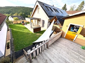 A residential property with a sloped roof, a wooden deck, and a fenced yard. - Ferienhaus Traumzeit by Kringe (Vöhl)