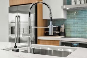 A modern kitchen with a stainless steel sink, a flexible faucet, and a visible dishwasher. - 1BR Retreat | Pool & Jacuzzi | Near Eagle Beach (Noord)