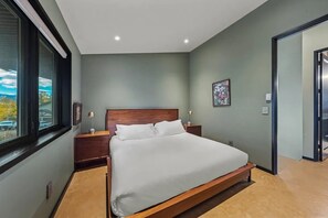Une chambre à coucher avec un lit, des tables de chevet, une fenêtre et une porte.