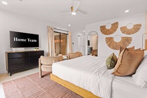 A modern bedroom with a bed, a TV, a dresser, and a seating area. - Lakin' It Easy | Luxe Waterfront Oasis | Sleeps 16 (Mesa)