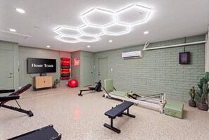 Ein Fitnessraum mit Trainingsgeräten, einem Fernseher und motivierenden Wandbildern.