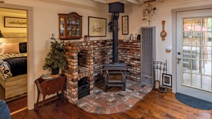 Una habitación acogedora con chimenea de ladrillo, un armario de madera y una puerta con panel de cristal.