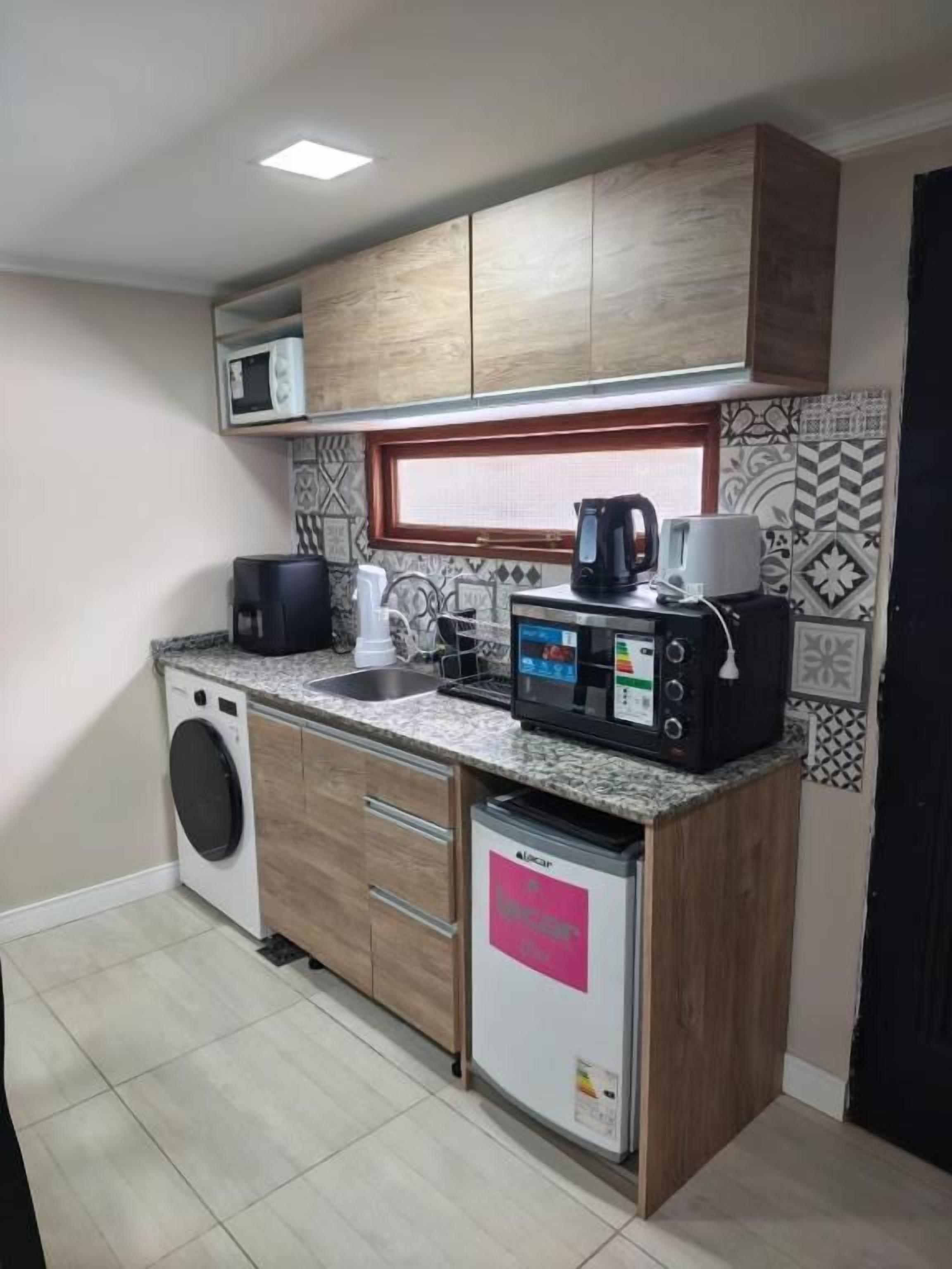 Una cocina compacta equipada con lavadora, cafetera y microondas.