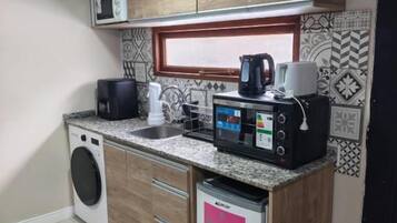 Una cocina compacta equipada con lavadora, cafetera y microondas.