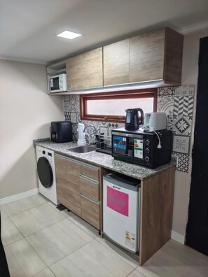 Una cocina compacta equipada con lavadora, cafetera y microondas.