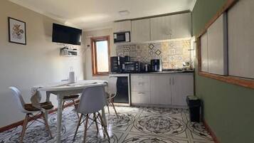 A compact kitchen with a dining area, a microwave, and a coffee machine.