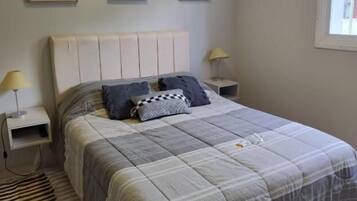Un dormitorio con cama, mesitas de noche, una ventana y decoración en la pared.