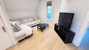 A modern living room with a sofa, coffee table, and a flat-screen TV. - Charming York Sanctuary with Private Rooftop Oasis (Toronto)