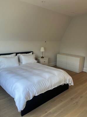 A bedroom with a large bed, bedside tables, a lamp, and a dresser. - Charming York Sanctuary with Private Rooftop Oasis (Toronto)