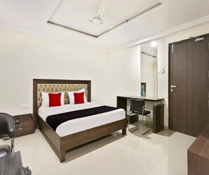 A hotel room with a bed, desk, chair, and wardrobe. - Classic Halcyon Deccan Inn (Hyderabad)