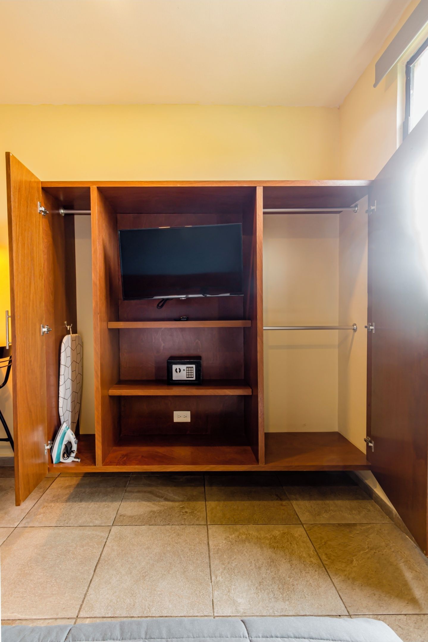 Un dressing avec des portes en bois, une tringle et un meuble de rangement.