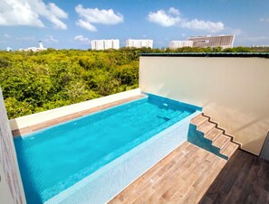Una piscina con un solarium in legno e vista sullo skyline urbano.