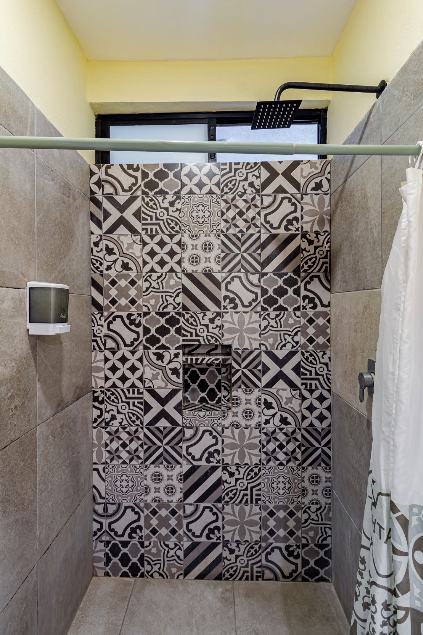 A shower area with patterned tiles and a handheld showerhead.