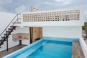 Una piscina en la azotea con diseño moderno, una escalera y vistas del paisaje circundante.