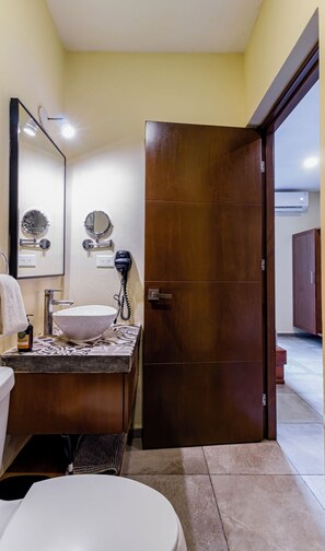 Un bagno con un lavandino bianco, uno specchio, un asciugacapelli e una porta in legno.