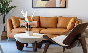 A modern living room with a brown leather sofa, a round white coffee table, and two brown chairs. - IDEALLY LOCATED JUST 100 METRES FROM THE ICONIC PALAIS DES FESTIVALS (Cannes)