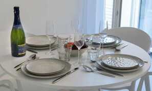 A round dining table set with plates, cutlery, glasses, and a bottle of champagne. - IDEALLY LOCATED JUST 100 METRES FROM THE ICONIC PALAIS DES FESTIVALS (Cannes)