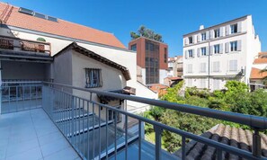 A residential building with a balcony, a tiled roof, and a view of neighboring houses. - IDEALLY LOCATED JUST 100 METRES FROM THE ICONIC PALAIS DES FESTIVALS (Cannes)