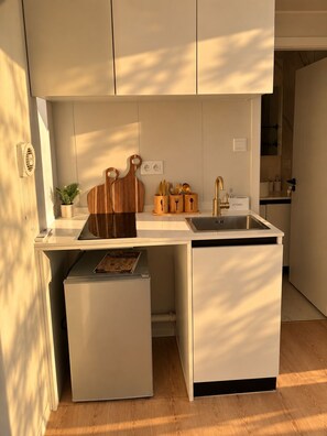 A compact kitchen with a built-in sink, a small refrigerator, and wooden cutting boards.