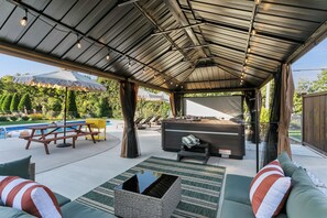 Eine Außenpatio mit Pool, Liegestühlen, Whirlpool und überdachter Sitzgelegenheit.