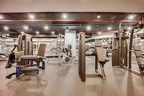 A gym with various exercise machines, including weight stacks and cardio equipment. - Refined 1BR Haven | Palm Jumeirah (Dubai)