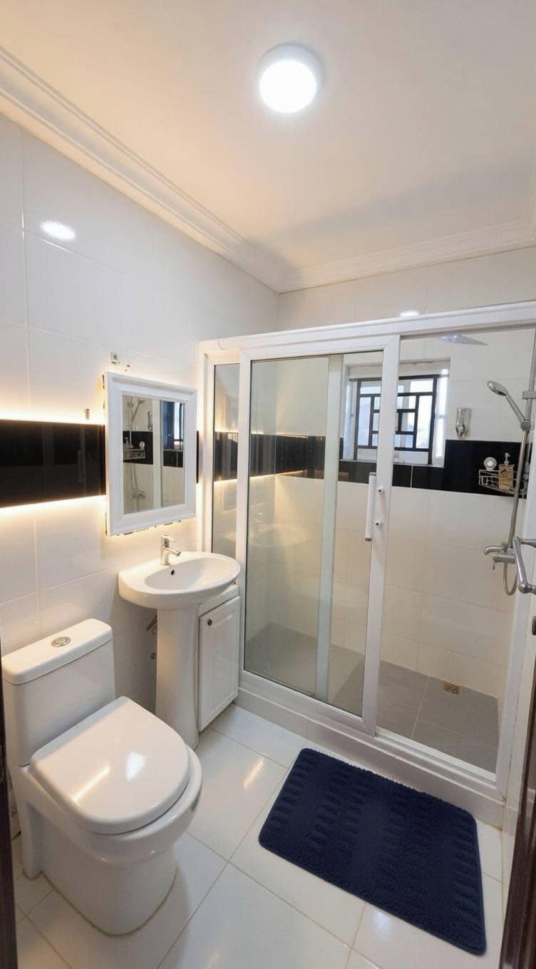 Un baño moderno con inodoro, lavamanos y ducha envuelta en vidrio.